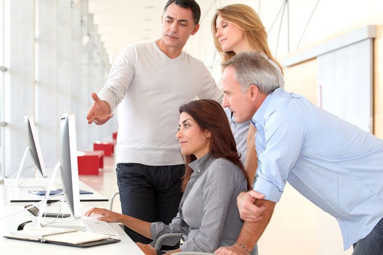 A group of professionals gathered around a computer screen.