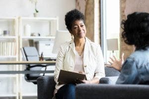 A licensed clinical social worker sits across from a client and listens to them speak.