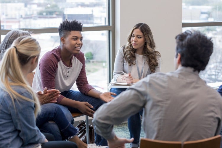 Teens in a circle speak with a mentor.